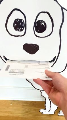 a person holding up a piece of paper with a drawing of a dog on it