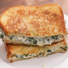 two grilled sandwiches stacked on top of each other with cheese and spinach toppings