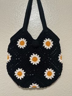 a crocheted black purse with white and yellow flowers