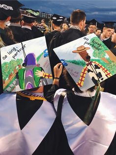 two graduates are holding their caps in the middle of a graduation ceremony, one is wearing a black and white striped gown