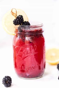 a mason jar filled with blackberry lemonade and blackberries