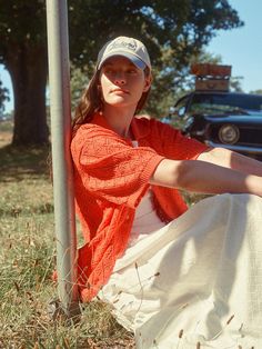 a woman sitting on the ground next to a pole