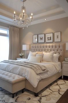 a bedroom with a large bed, chandelier and pictures on the wall above it