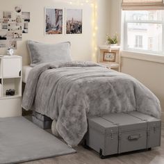 a bedroom with a bed, dresser and window covered in grey fur blanketed blankets