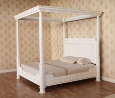 a white bed sitting on top of a hard wood floor next to a wallpapered wall