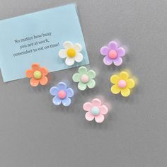 small plastic flowers next to a note on a gray surface with the words no matter how busy you are at work, remember to eat on time