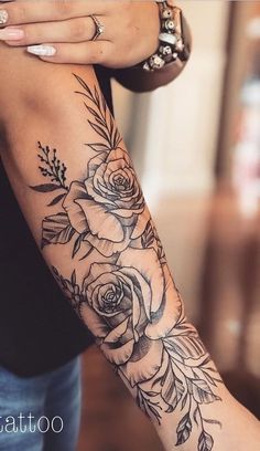 a woman's arm with flowers and leaves tattooed on her left arm by tattootoo