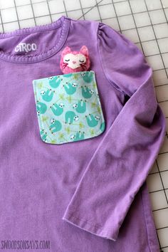 a purple shirt with a cat in the pocket