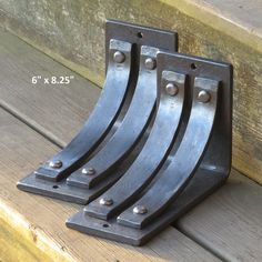 four metal brackets are sitting on a wooden bench