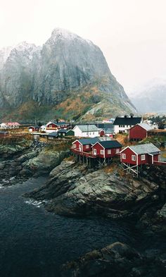 some red houses are on the rocks by the water