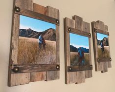 three wooden frames hanging on the wall with pictures of people walking through grass and mountains