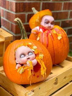 two small pumpkins with babies in them sitting on wooden pallets next to each other