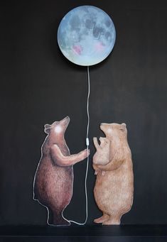 two bears are playing with a balloon in front of the moon