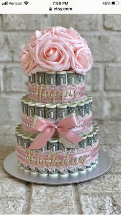 a cake made out of money with pink roses on top