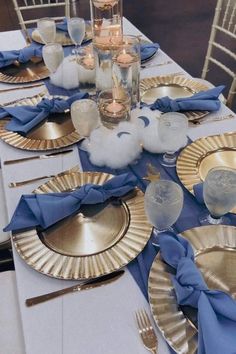 the table is set with gold plates and blue napkins