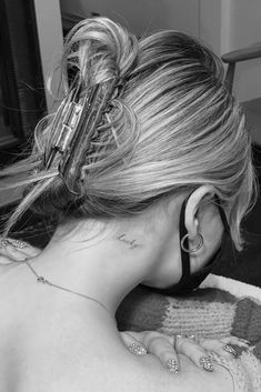 black and white photograph of woman with ear piercings on her back, looking at mirror