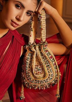 Inspired by opulent encrusted legacy jadau and polki jewelry, the Amara potli pouch ruby emerald is embellished with semi-precious rubies, emeralds, stones, nuggets with kundans and lustrous gold silver Japanese beads. It is finished with delicate asymmetrical handmade tassels at the bottom. The addition of our signature embellished handle makes it a statement piece. This functional piece of art fits in your essentials like a smartphone, makeup, keys, currency and cards. Japanese Beads, Potli Bags, Polki Jewellery, Ruby Emerald, Western Wedding, Wedding Service, Bride Bridal, Black Bow, Jewel Tones