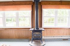 an old fashioned stove is in the middle of a room with wood paneling on the walls