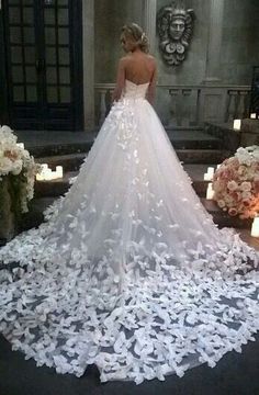 a woman in a wedding dress standing next to some flowers and candles on the ground