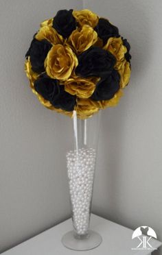 a vase filled with black and yellow flowers on top of a white shelf next to a wall