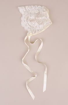 a white bridal garter hanging on a wall next to a ribbon tied around it