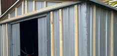 a motorcycle is parked in the open door of a storage shed that's being built