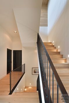 the stairs are made of wood and have black railings on each side, leading up to the second floor