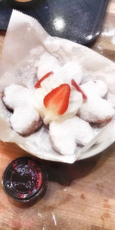 a plate topped with powdered sugar covered pastries next to a jar of jam