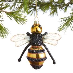 a glass ornament hanging from a christmas tree with a bee decoration on it