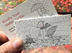 someone is holding up two business cards that are designed to look like children's umbrellas