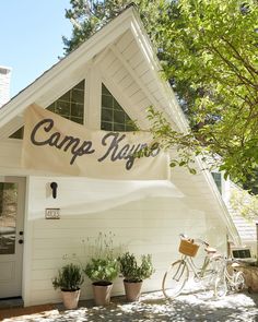 a bicycle is parked in front of a white building with a sign that says camp neugo