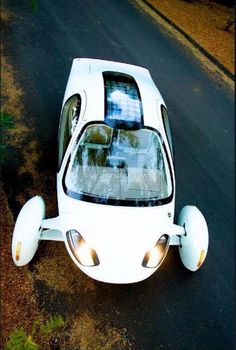 a small white car driving down a street