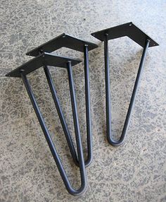 two black metal brackets sitting on top of a floor