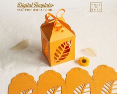 an orange paper box with cut out leaves on it and some flowers next to it