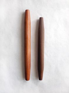 two wooden objects sitting next to each other on a white surface, one is brown and the other is wood