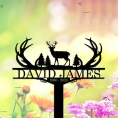 a deer is standing on top of a sign with trees and flowers in the background