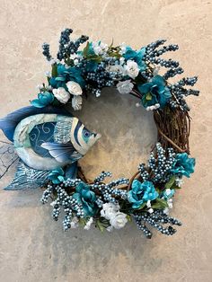 a wreath with blue and white flowers on it is sitting on the floor next to a wall