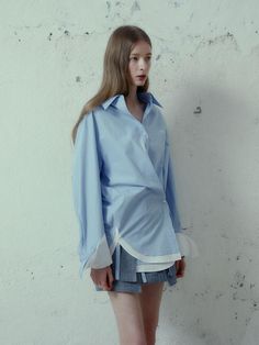 This product is a creative take on the classic button-up shirt, featuring double-layered cuffs that give it a unique and avant-garde appearance. The relaxed fit ensures a comfortable drape over the body, while the detail-oriented design speaks to a modern, fashion-forward aesthetic. The ensemble is complemented by a pair of tailored shorts that balance the shirt's volume and add to the contemporary styling of the set. - The shirt's double-layered cuffs create a distinctive style statement, setting it apart from traditional designs.- A relaxed fit allows for effortless pairing with various bottoms, ensuring versatility in styling options.- Tailored shorts provide a structured contrast to the shirt's loose form, resulting in a balanced and polished outfit.- Constructed with a focus on q Spring Long Sleeve Tops With Striped Cuffs, Summer Workwear Tops With Striped Cuffs, Summer Tops With Striped Cuffs For Workwear, Spring Daywear Top With Striped Cuffs, Chic Cotton Shirt For Layering, Spring Daywear Tops With Striped Cuffs, Classic Spring Blouse With Striped Cuffs, Spring Shirt With Roll-up Sleeves And Fold-down Collar, Spring Button-up Shirt With Striped Cuffs