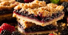 berry crumbler bars stacked on top of each other with fresh berries around them