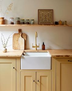 a white kitchen sink sitting under a wooden shelf next to a cutting board on top of a counter