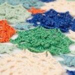 multicolored crocheted doily on tablecloth with white and blue edges