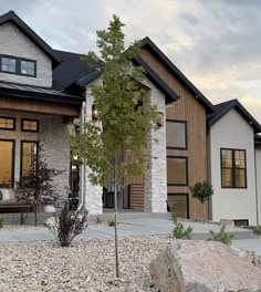 a house that is next to some rocks and trees in front of it with the door open