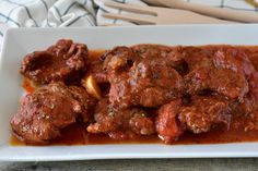 a white plate topped with meat covered in sauce