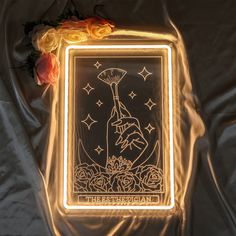 the illuminated taroti card is on display next to roses and a rose bush