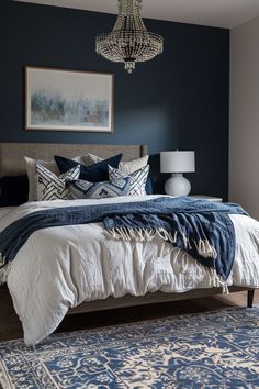 a bedroom with blue walls and white bedding, chandelier above the bed