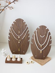 two wooden jewelry stands with pearls and necklaces on them