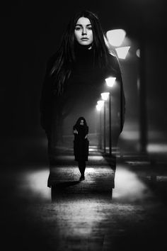 a woman walking down the street at night with her long hair blowing in the wind