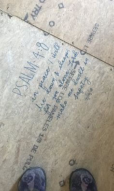 someone's feet in blue shoes standing on the floor next to a sign with writing on it