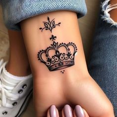 a woman's foot with a crown tattoo on it