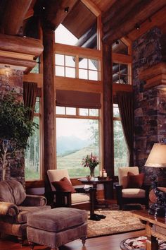 a living room filled with lots of furniture next to a stone wall and wooden ceiling